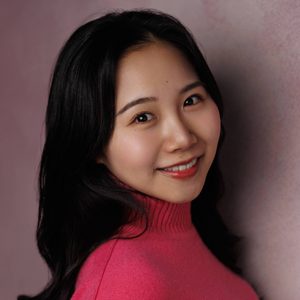 Em is smiling at the camera. She is wearing a bright pink top.