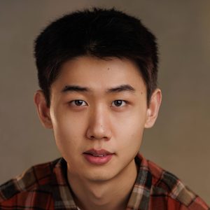 KJ is looking at the camera. He is wearing a chequered shirt.