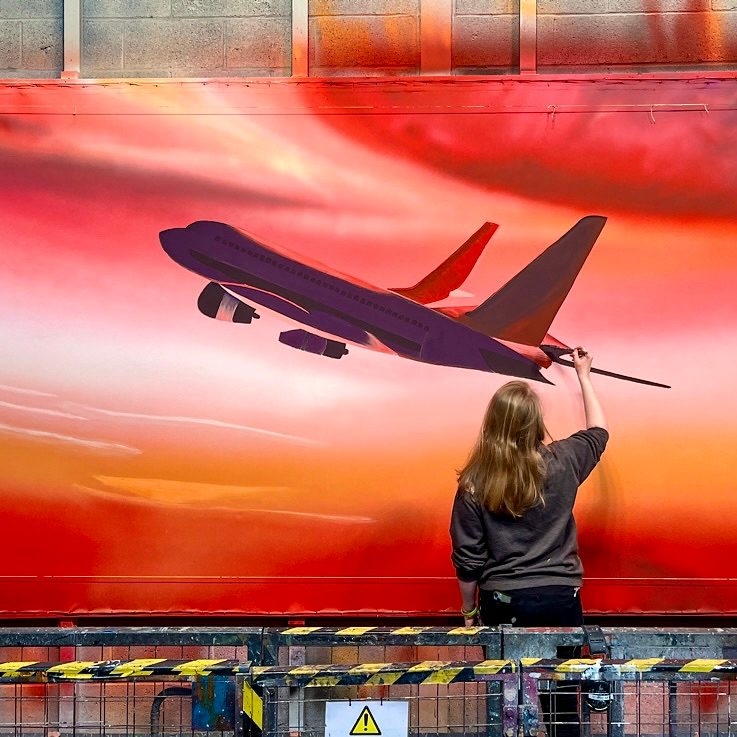 Rebecca is painting a scenic mural.
