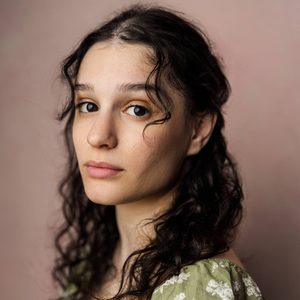 Shoshana is looking at the camera.