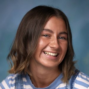 Emma May Crone is smiling at the camera. She is wearing a striped top.