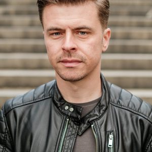 Will is looking at the camera. He is wearing a leather jacket.